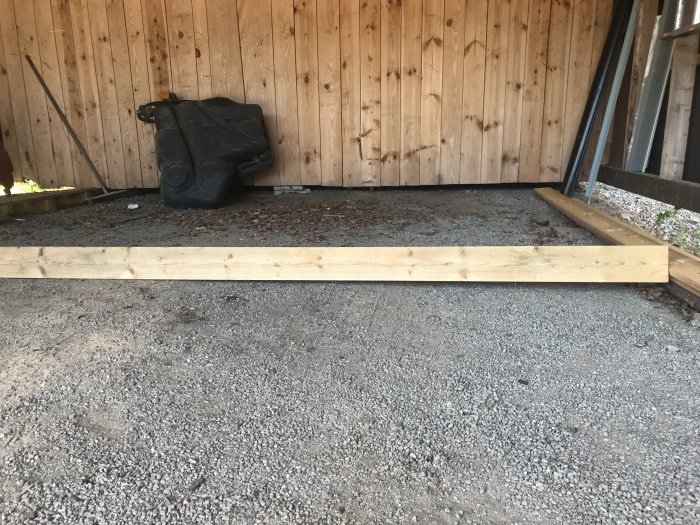 Carport i trä med grusgolv och förberedelse för betonggjutning.