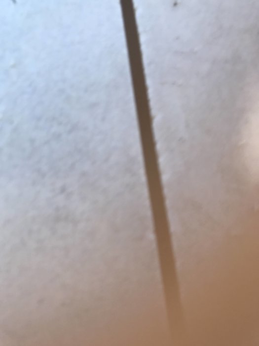 Närbild på en skarv mellan två golvplattor som är så fint skuren att den nästan är osynlig.