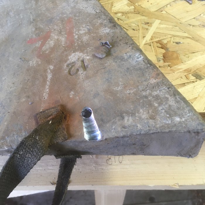 Ett nyligen borrat hål i metall med borr och skälp för ränna, ovanpå en arbetsbänk.