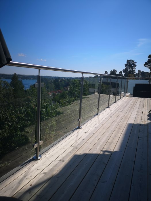 Altan med glas och metallräcke som vinglar, med utsikt över en sjö och landskap i bakgrunden.