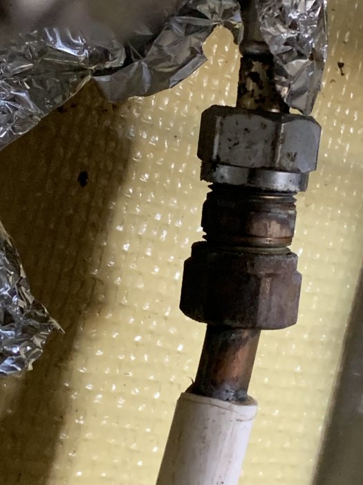 Rostig röranslutning till köksblandare med temporär aluminiumfolielösning.