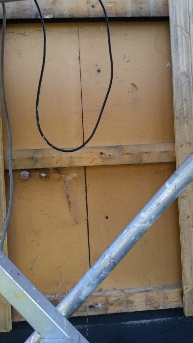 Delvis upptagen innerfasad med synliga spikar och tecken på mögel och korrosion.