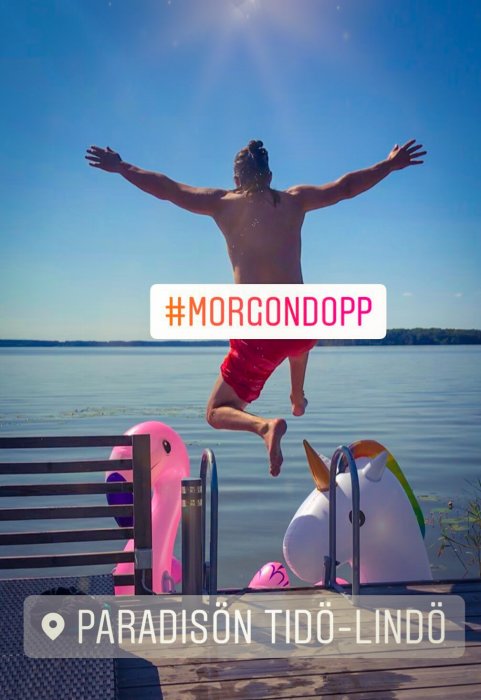 Person hoppar från brygga i solsken för ett morgondopp vid Mälaren, uppblåsbara leksaker syns.