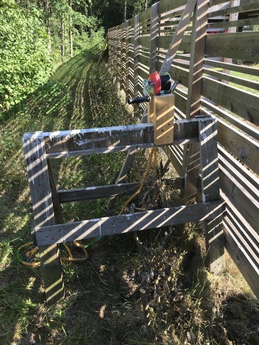 Båtvinsch från Biltema monterad på en träkonstruktion vid staket för att dra upp buskage.