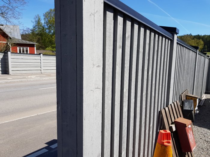 Bullerplank med t-formade toppar nära en väg, byggt i virke med täta paneler för att dämpa ljud.