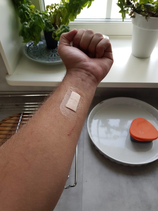 Arm med plåster och en lätt skada visande konsekvenser av arbete med vinkelslip.