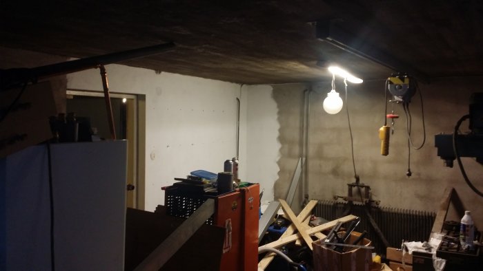 Halvfärdigt garage med ojämnt målad vägg och utspridda verktyg samt byggmaterial.