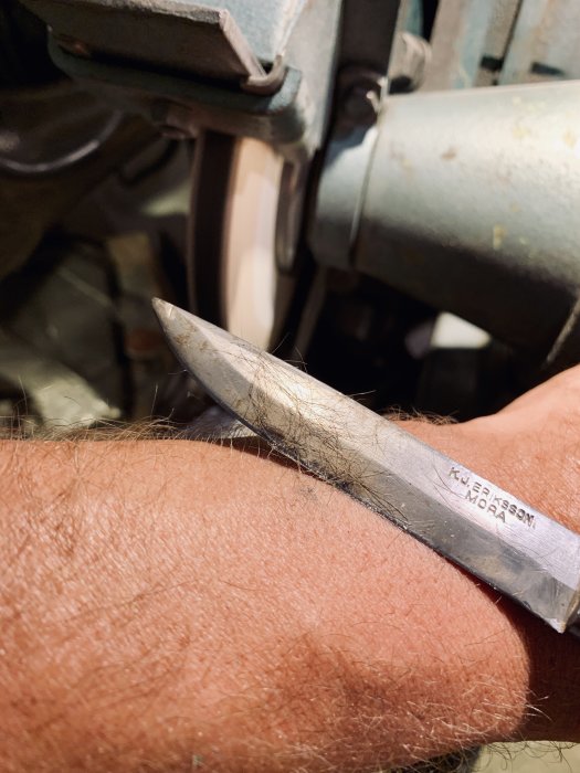 Morakniv som testas för skärpa på underarm efter slipning med polerskiva.