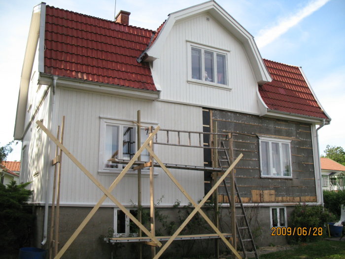 Renovering av ett hus från 1938, byte av syll och plank på fasaden, ställningar runt byggnaden.