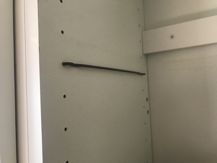 En 21 cm lång hyllbärare i ett tomt köksskåp med flera förborrade hål för hyllplan.