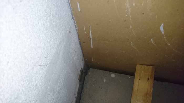 Glipa mellan betongvägg och golv i källare, med gammal golvsockel och synliga kablar.