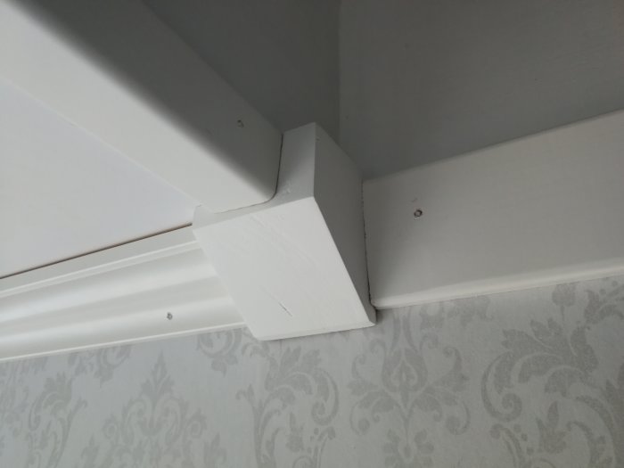 Hantverksmässigt tillverkad hörnkloss som sammanfogar lister i ett takhörn, limmad och slipad, före fogning och målning.