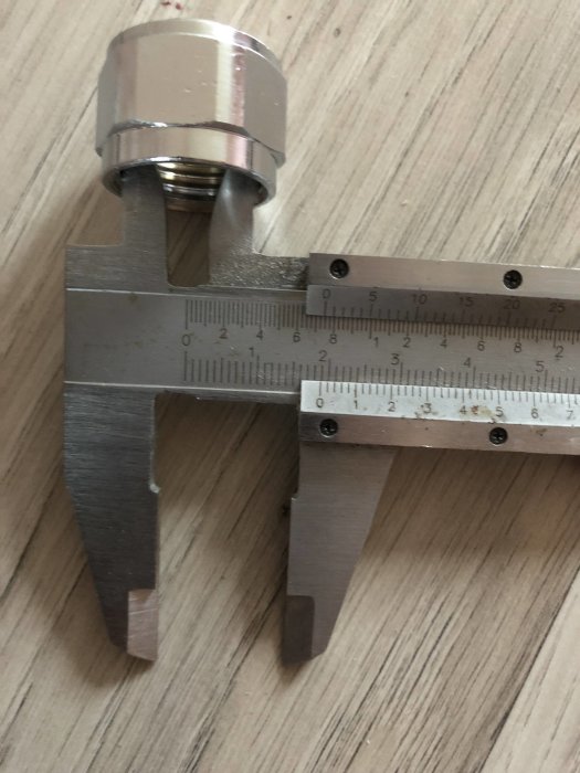 Halvkoppling mäts med en skjutmått mot ett trägolv, visar 19mm istället för förväntade 20mm.