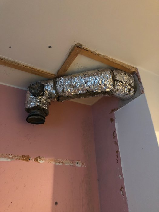 Isolerat ventilationsrör som sticker ut från en vägg i ett renoveringsprojekt.