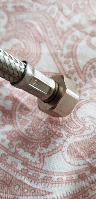 Närbild på en GROHE Quadra krananslutning utan packning mot blommigt tyg.