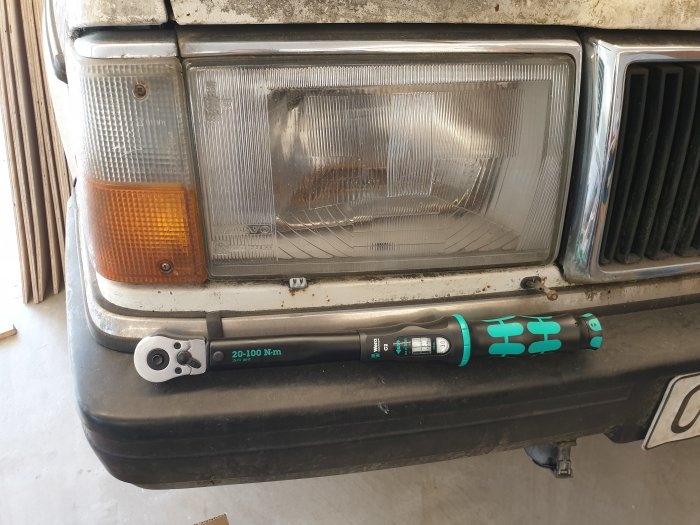 Wera C2 1/2" 20-100Nm momentnyckel ligger framför en bilens strålkastare och stötfångare.