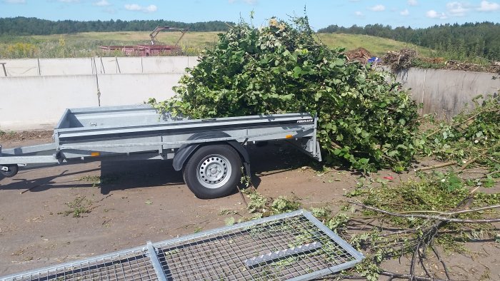 En släpvagn fylld med grenar och trädgårdsavfall vid en tippanläggning.