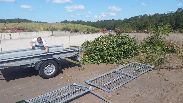 En person som tömmer släpvagn full av trädgårdsavfall på en återvinningscentral.