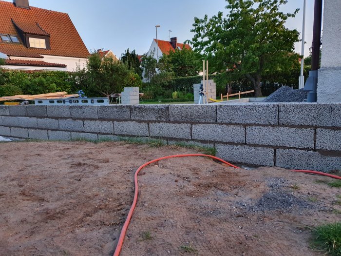 Ny murad stödmur på en terrass under konstruktion med grus och byggmaterial i bakgrunden.