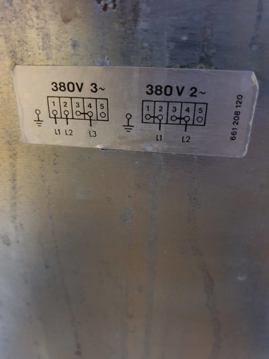 Kopplingsscheman för 380V 3-fas och 2-fas på en etikett mot en metallbakgrund.