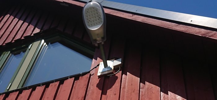 Strålkastare monterad under taknock på en byggnad med synliga elkablar och dosor.