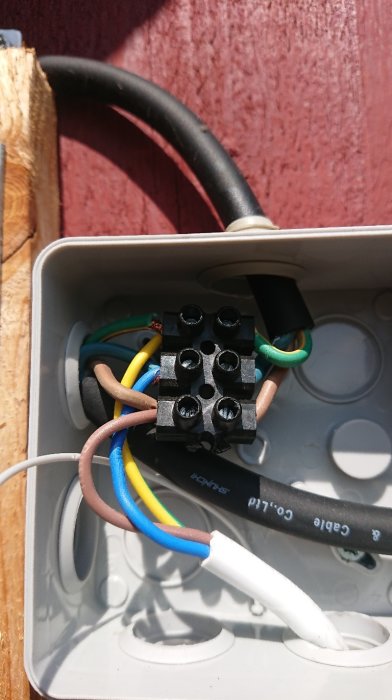 Elkopplingar i dosa med sockerbitar och flera färgade elkablar synliga.