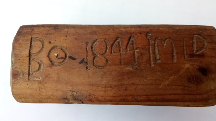 Träblock med inskrift "Bo-1841MD" som ägaridentifiering, slitet, av gran eller furu.
