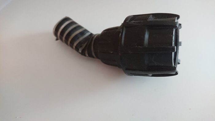 Svart plastkoppling med skadad sugslang på vit bakgrund, anpassad för vattenpump med gänga.