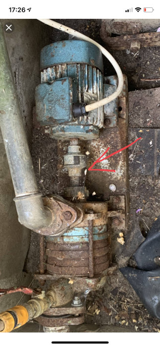 Motor och pumpmekanism med en röd pil som pekar på en axel som ska vara möjlig att vrida för hand.