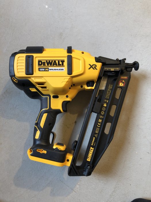 En DeWalt 18V spikpistol ligger på ett betonggolv, redo att användas för att spika panel.