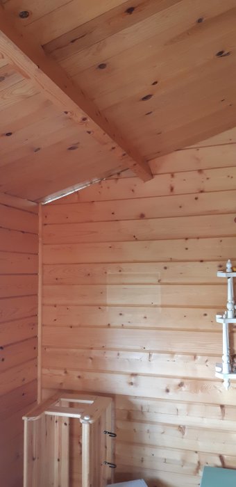 Interiör av friggebod med öppning mellan tak och vägg, synlig luftvärmepumpssäkring.