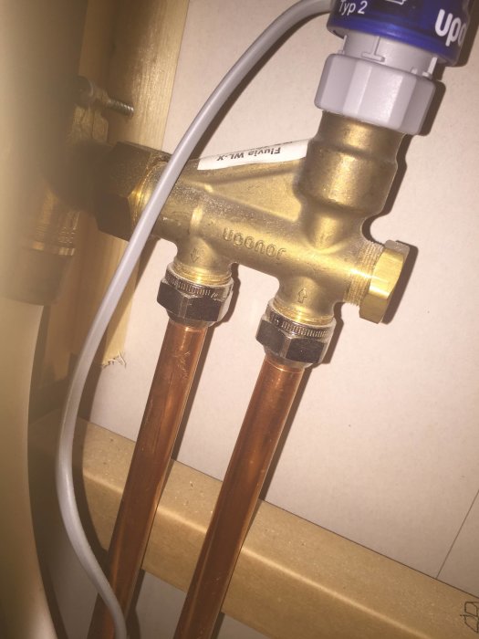 Golvvärmefördelare med anslutna kopparrör och elektrisk kabel för en Fluvia push-installation.