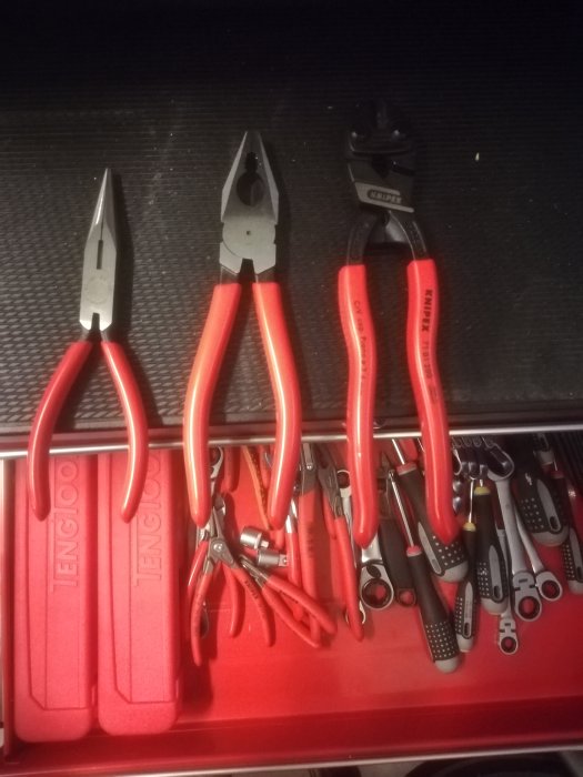 Tre nya Knipex-tänger med röda handtag bredvid andra verktyg i en verktygslåda.