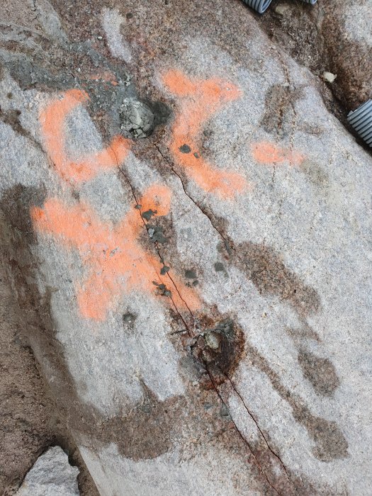 Berg med orange markering och sprickor för beredning inför sprängning.