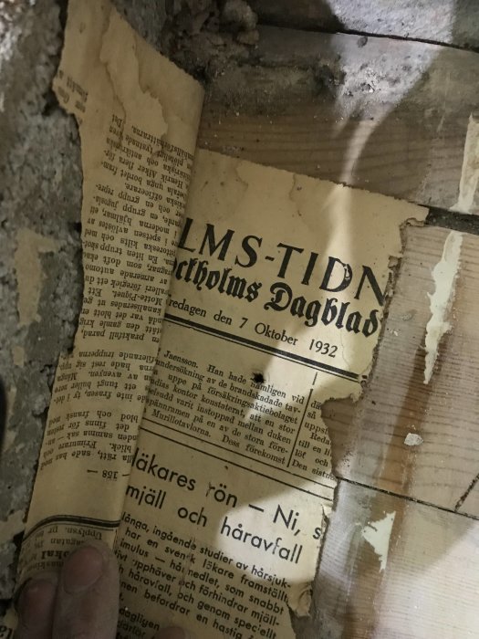 Gammal tidningssida från 'Stockholms-Tidningen' daterad den 7 oktober 1932, funnen under golvbeläggning under renovering.