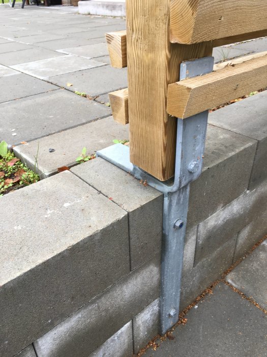 Metallstöd som håller en trästolpe vid en betongtrappa.