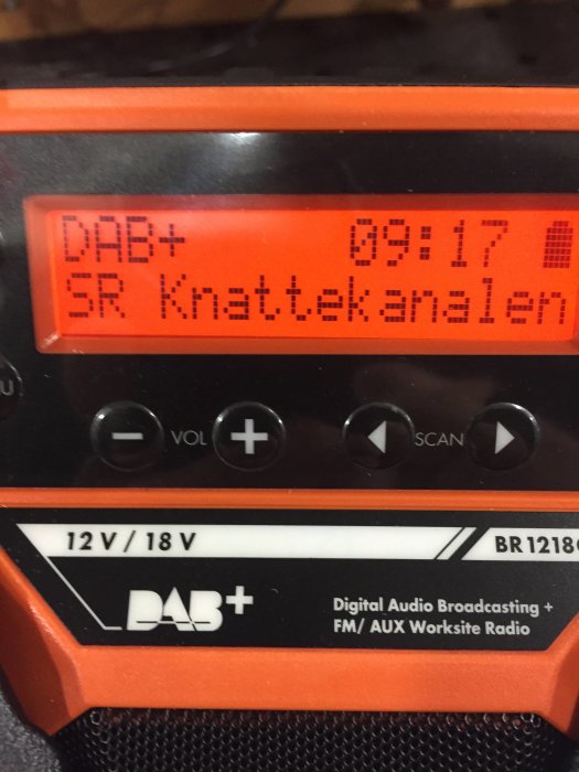 Närbild av en portabel DAB/FM-radio som visar display med DAB+ och text "SR Knattekanalen".