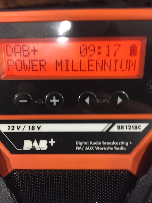 Orange och svart DAB-radio med digital display som visar 'POWER MILLENNIUM DAB+' och tid '09:17'.