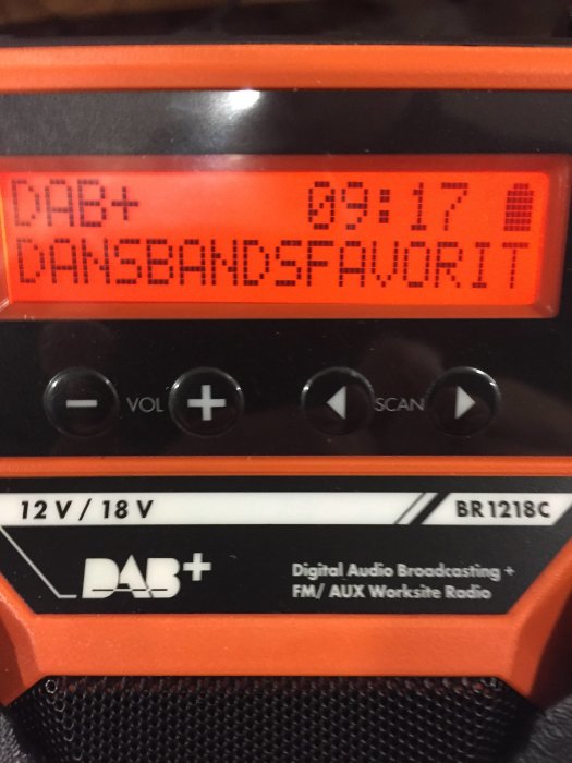 Närbild av en orange DAB+ arbetsradio med texten "DANSBANDSFAVORIT" på displayen.