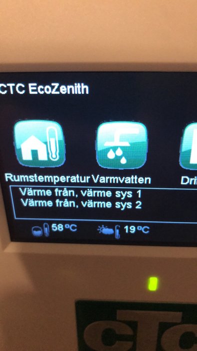 Display på värmesystem med text "Värme från, värme sys 1 & 2", rumstemperatur 19°C, panna 58°C.