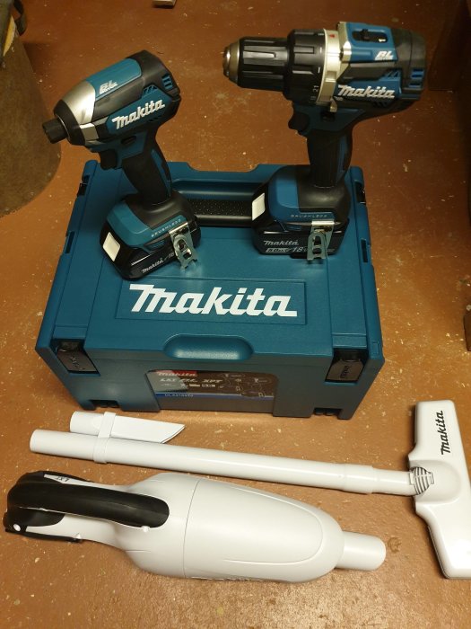 Nytt Makita-skruvdragarset på en blå låda med två skruvdragare, extra batterier och en vit Makita-dammsugare framför.