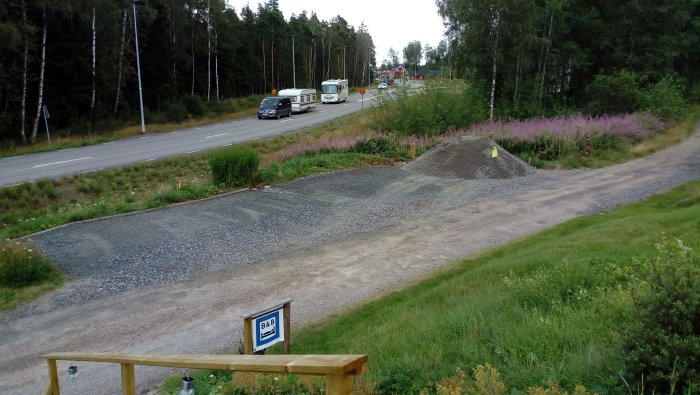 Grushög vid infart nära trafikerad väg med passerande fordon och skylt för B&B.