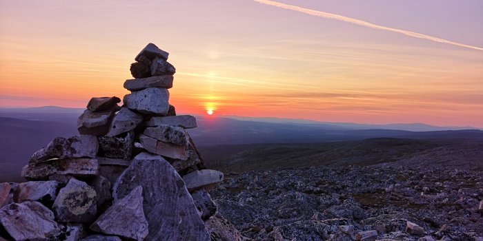 Stenröse i förgrunden med solnedgång bakom över ett bergslandskap i Vemdalen.