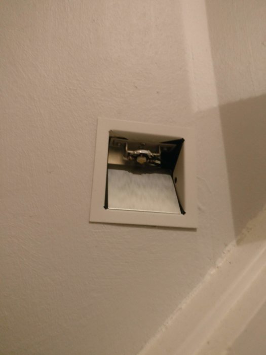 Öppnad vägglampa lågt monterad vid trappsteg med synlig ljuskälla och ledningar.