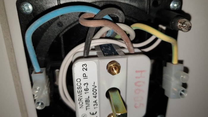 Närbild på en elkontakt med märkningen NORWESCO, anslutna kablar och en monteringsplint.