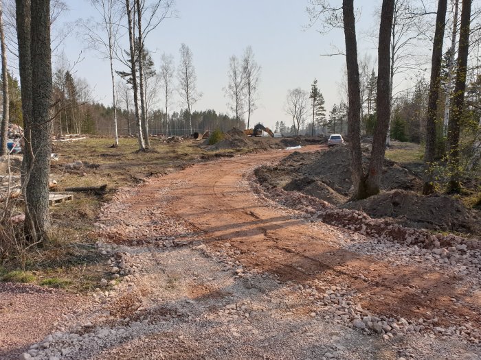 Infart med nylagd fiberduk omgiven av grävda jordhögar vid en byggarbetsplats.