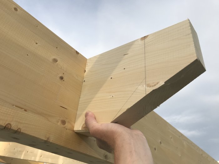 Hand håller träbit vid anslutning till annat trä i en konstruktion, möjligt alternativ till balksko.