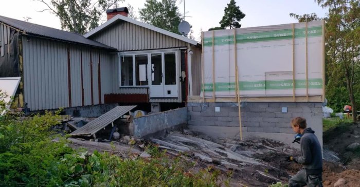 Renoveringsprojekt med nya väggar och grunder runt ett hus, gammal altan delvis riven.