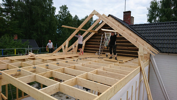 Personer bygger en trästomme till en tillbyggnad på ett hus.