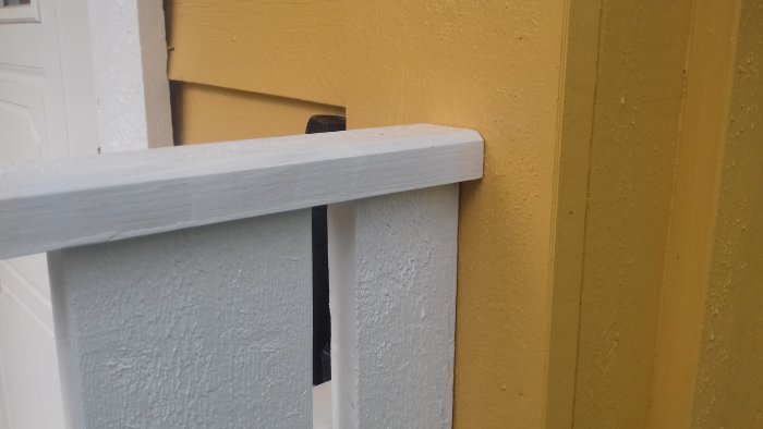 Högt byggt räcke i vitt och gult som skyddar mot snö, närbild på vinkelbeslag.